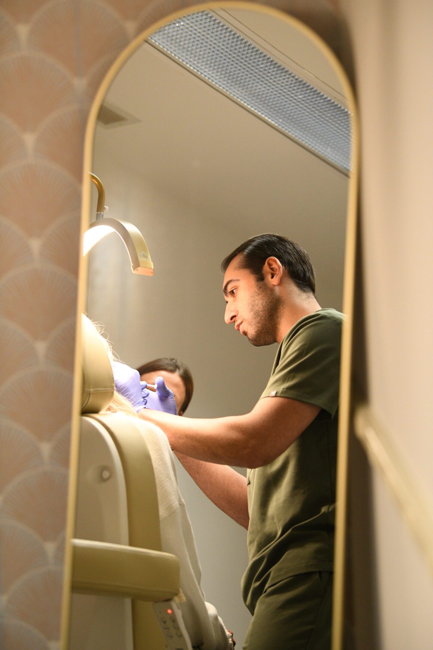 Dentist treating patient reflected in mirror