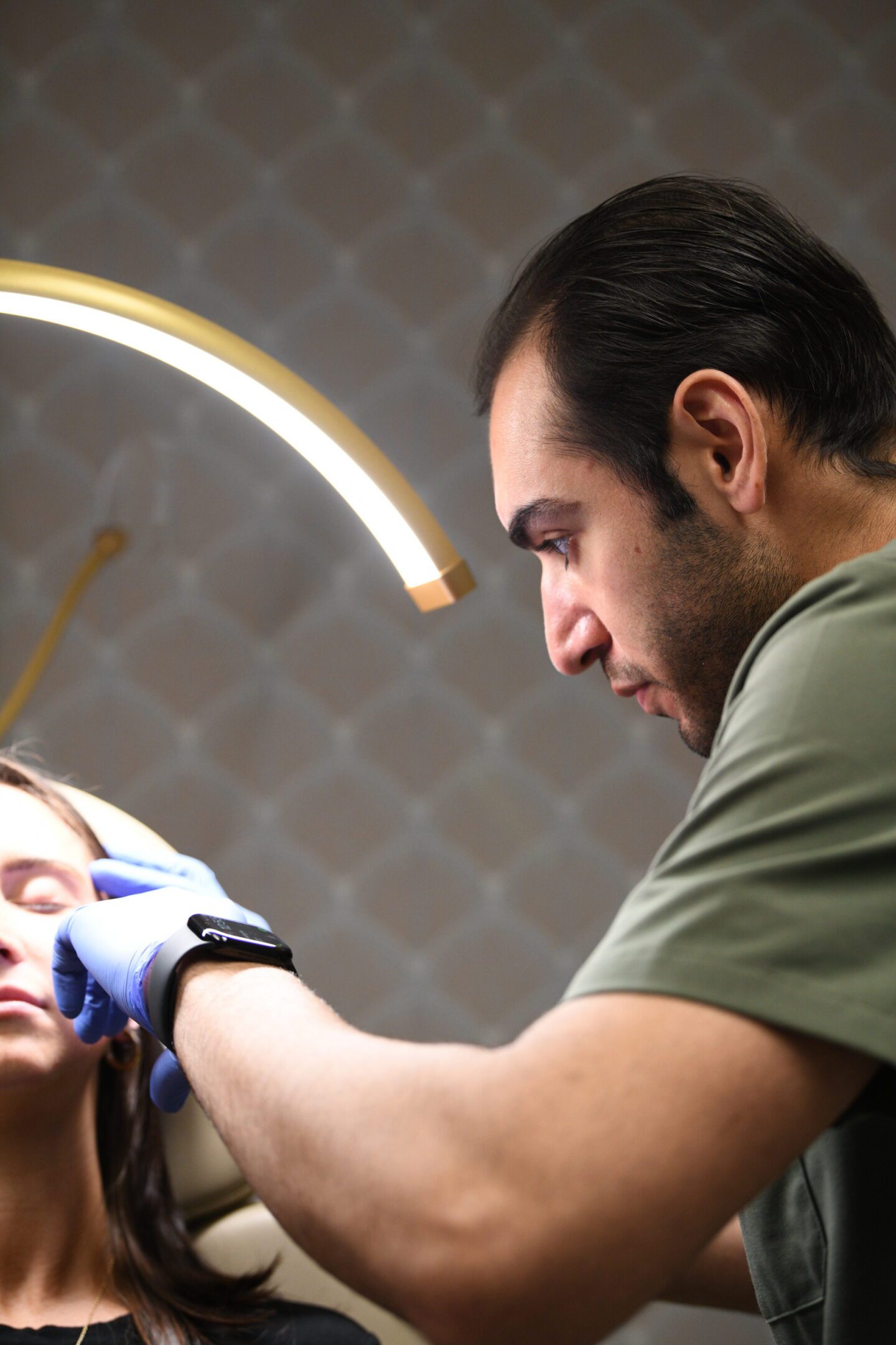 Clinician performing facial treatment under ring light